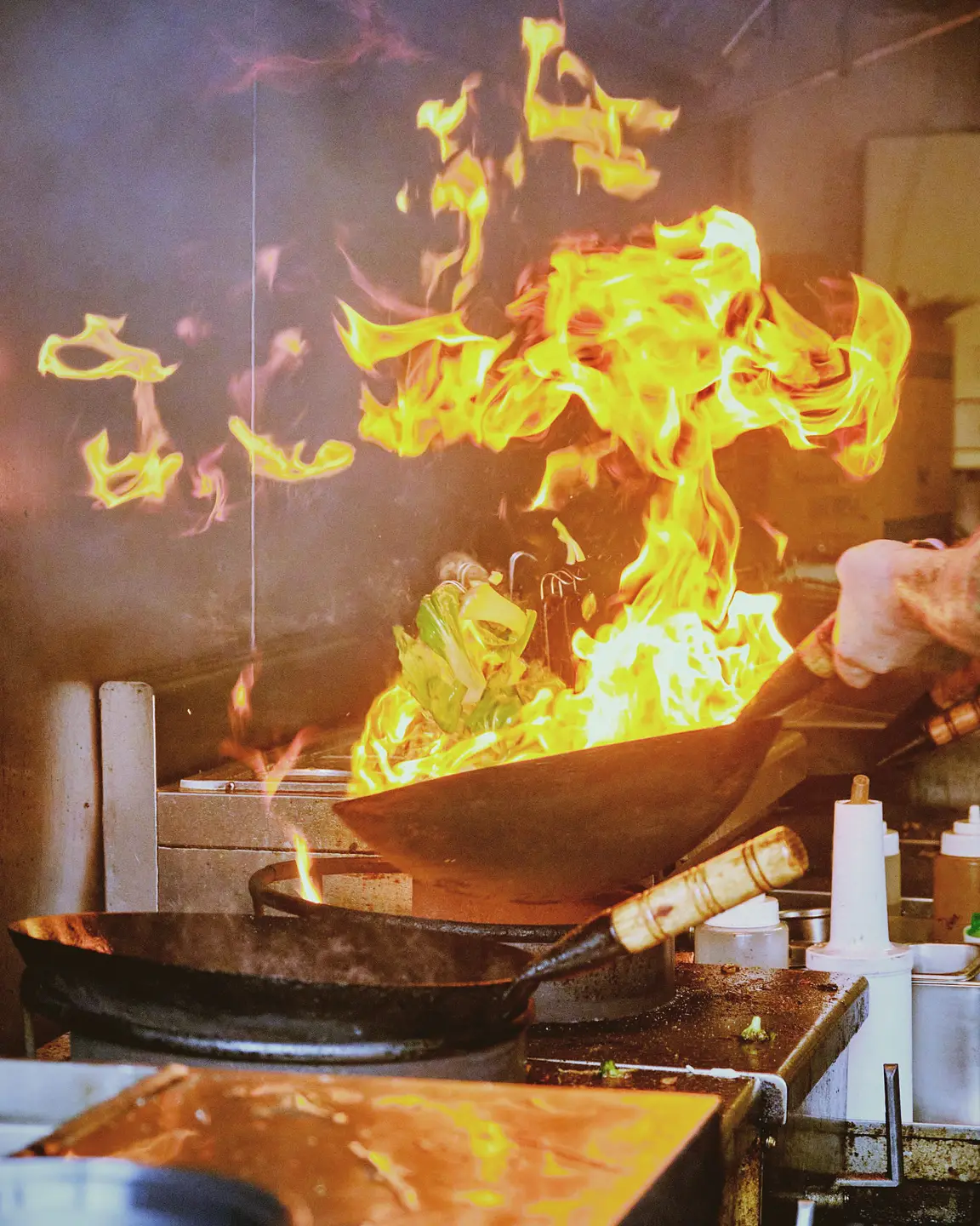 Tall flames rising from a pan over a gas stove