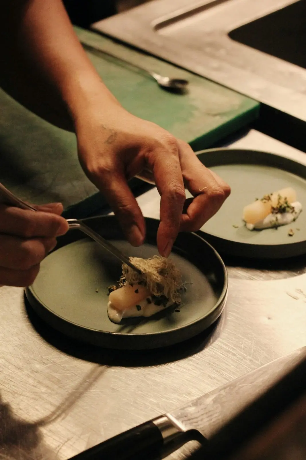 A chef finishing a plate with tweezers